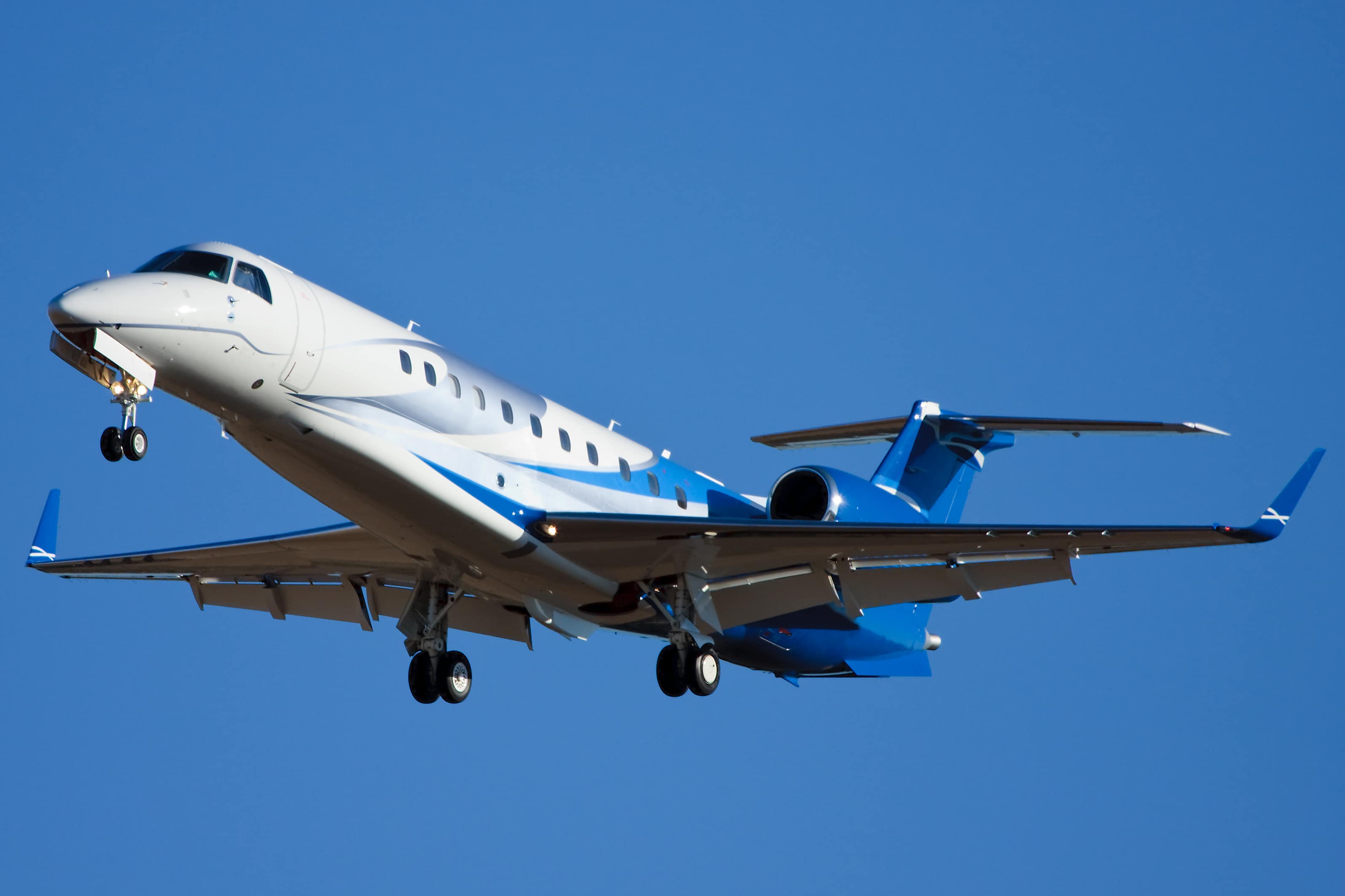 Embraer Legacy 600 de couleur bleue en train d'atterrir sur un aéroport.