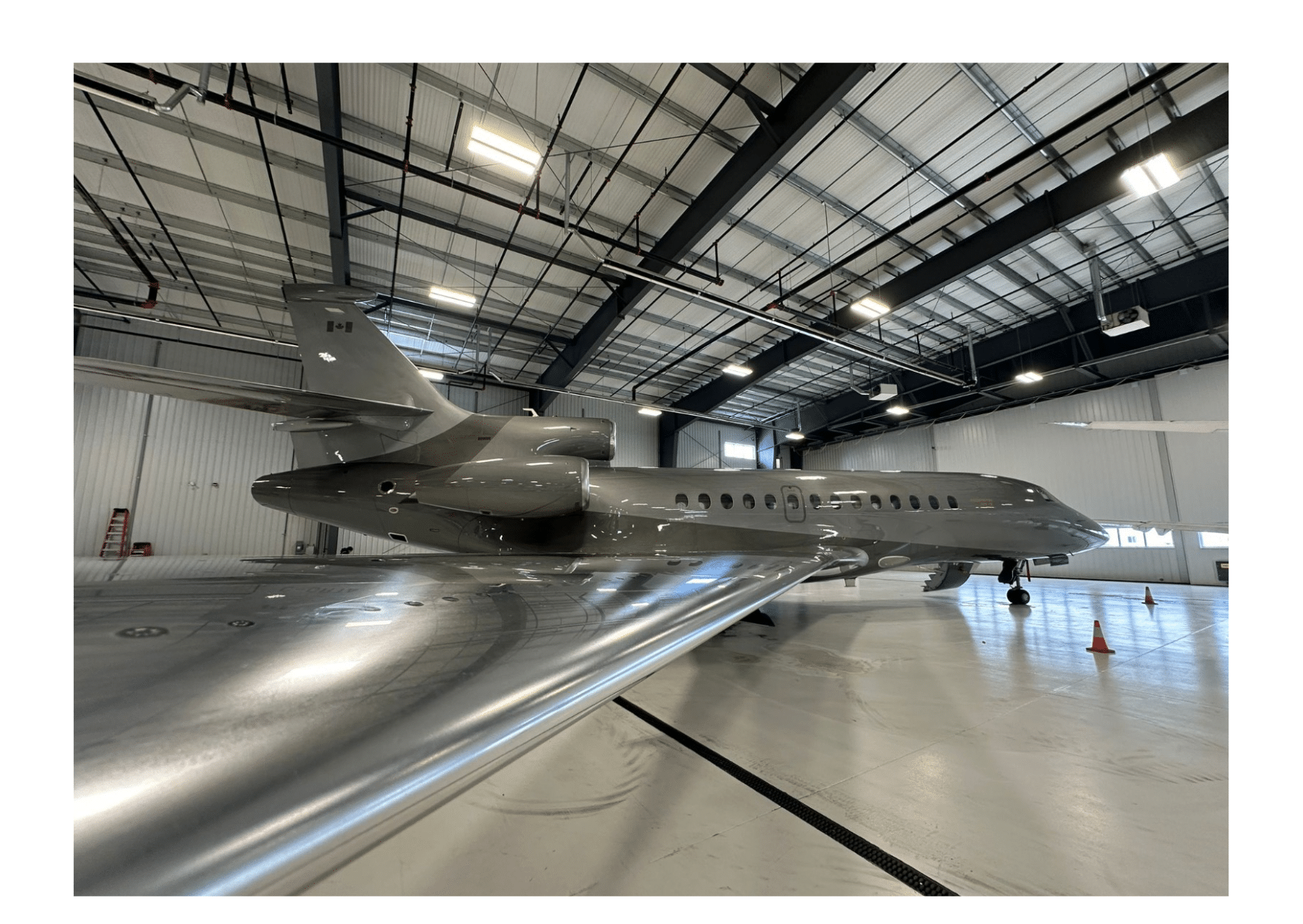 Un avion gris est parker dans un hangar réservé aux avions.Location d'avions privés