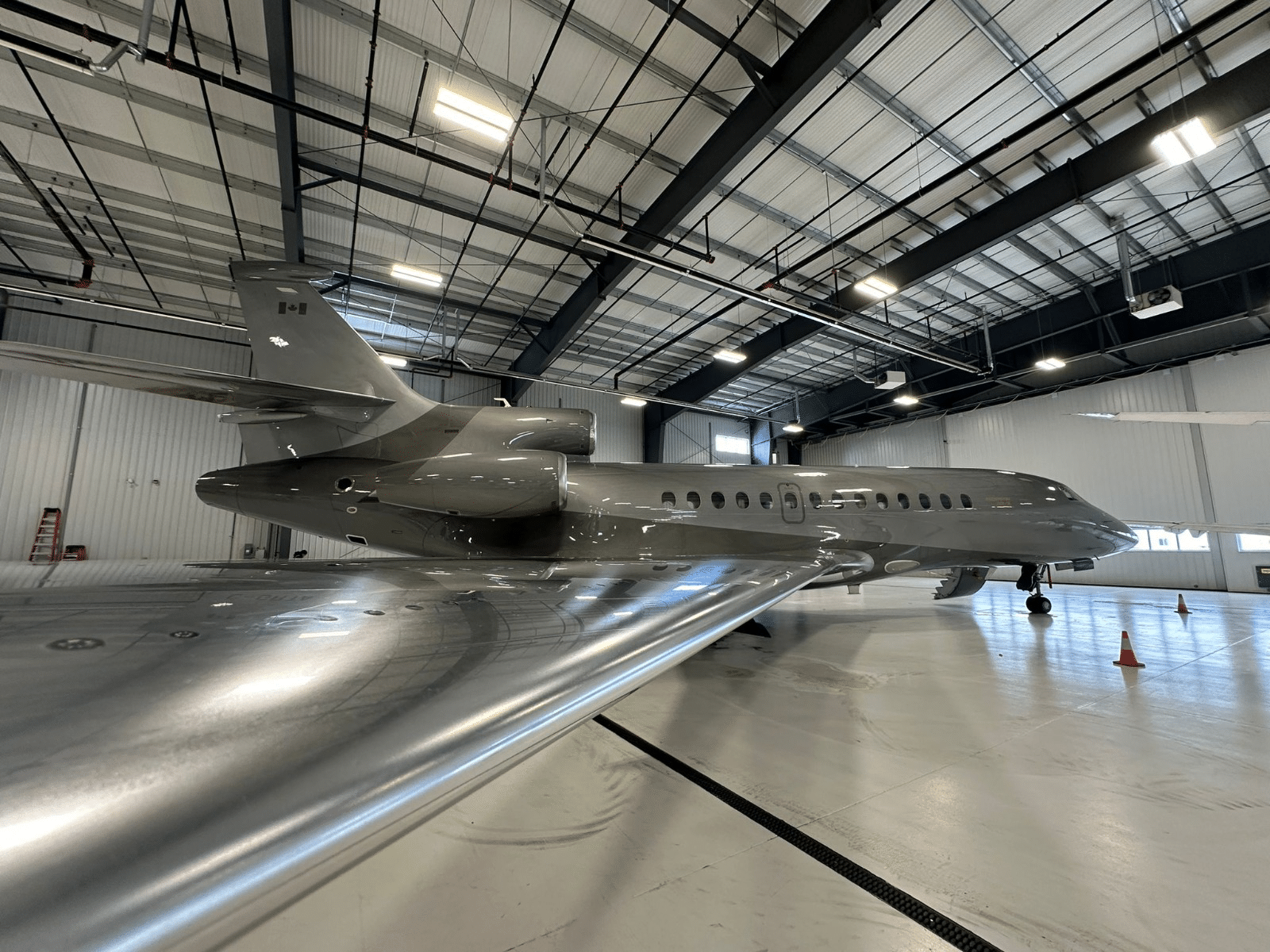 Un avion gris est parker dans un hangar réservé aux avions.
